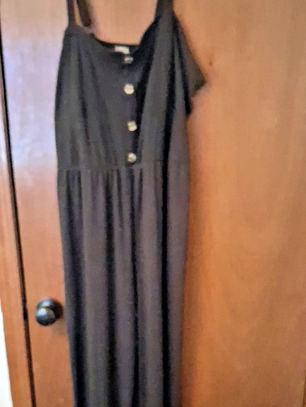 black wide leg jumpsuit with 4 brown buttons down the center.